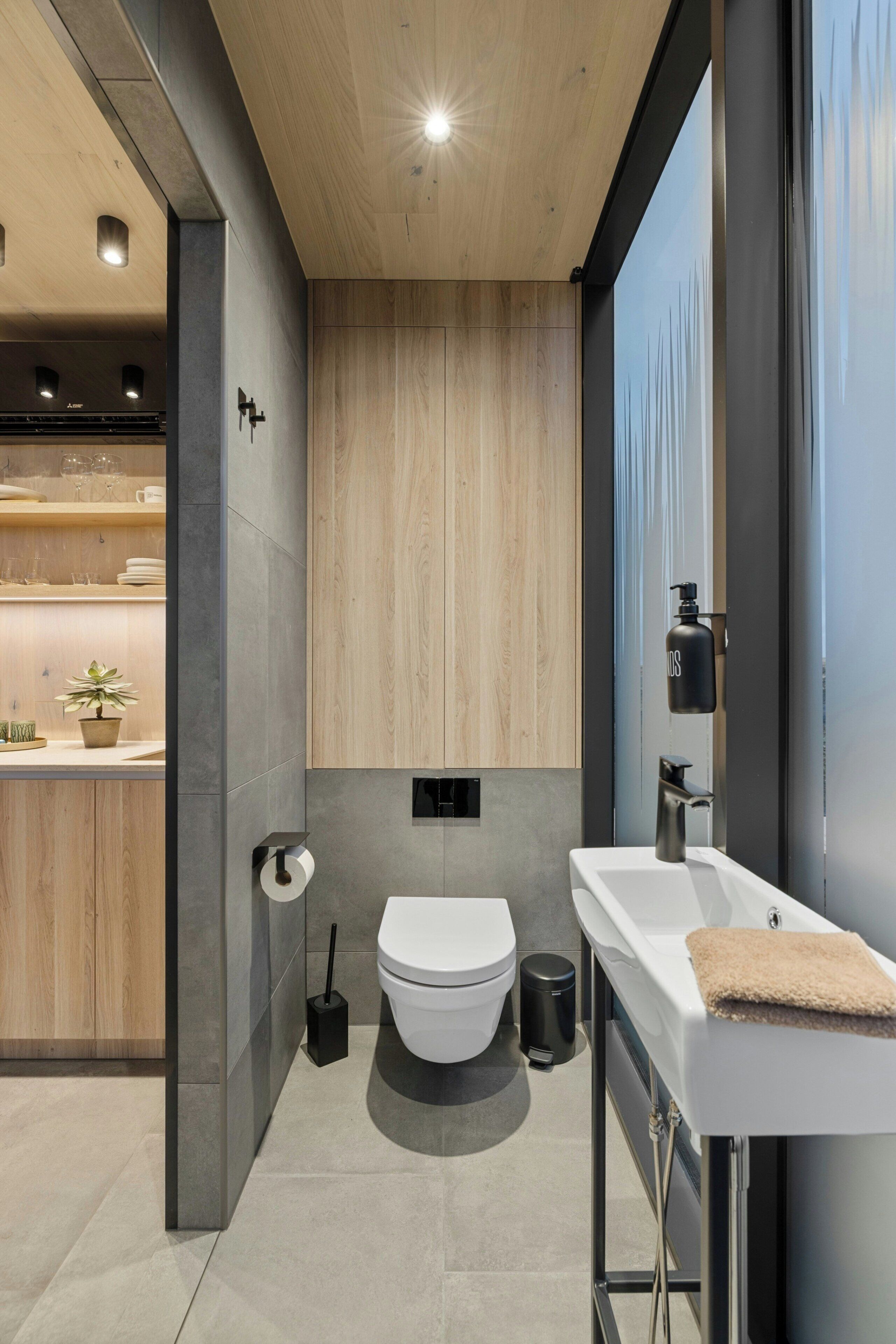 A modern bathroom with a toilet, sink, and storage cabinet.