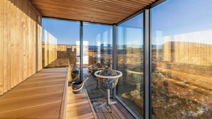 Ein modernes Interieur mit großen Glasfenstern, Holzböden und Blick auf die umliegende Landschaft.