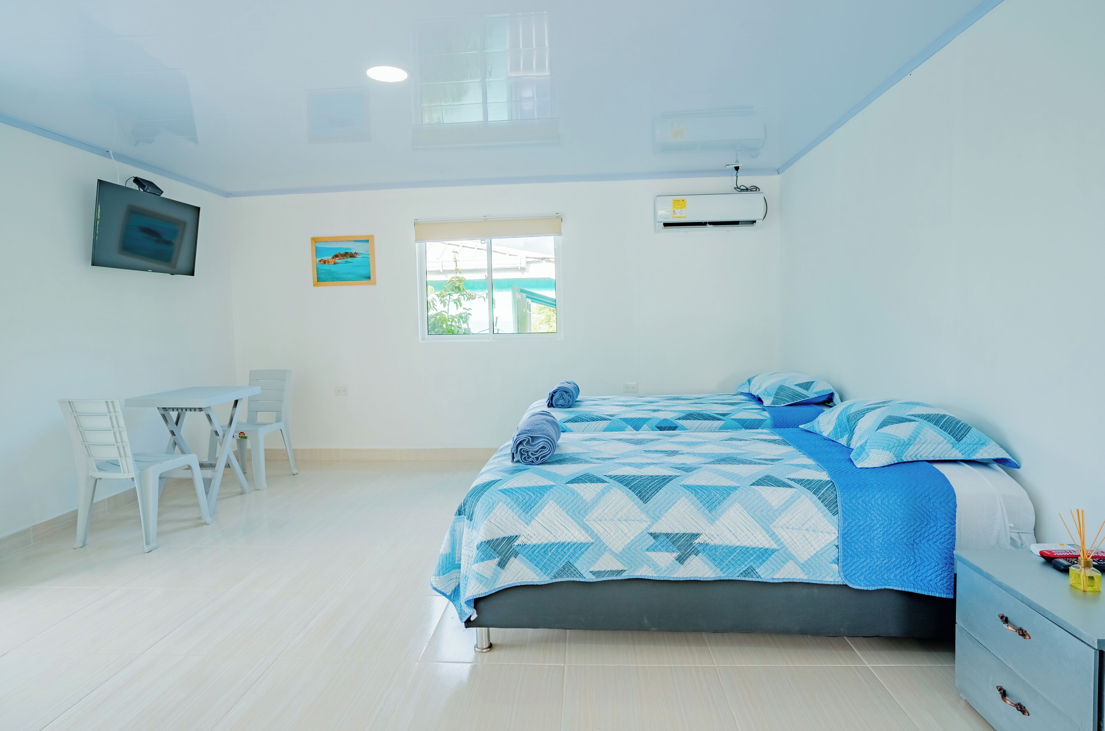 A bedroom with a bed, a desk, and a chair. There is a window with a view of greenery outside.
