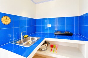 A kitchen with blue tiles, a stainless steel sink, a stove, and a dish rack with plates and utensils. - SHAMAR LODGE  (Providencia)