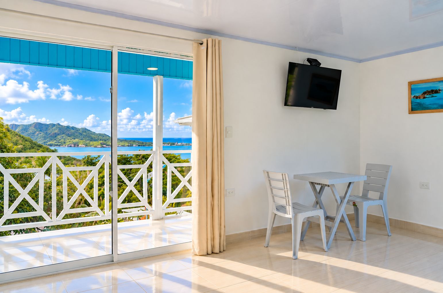 Et værelse med balkon, fjernsyn og et bord med stole.