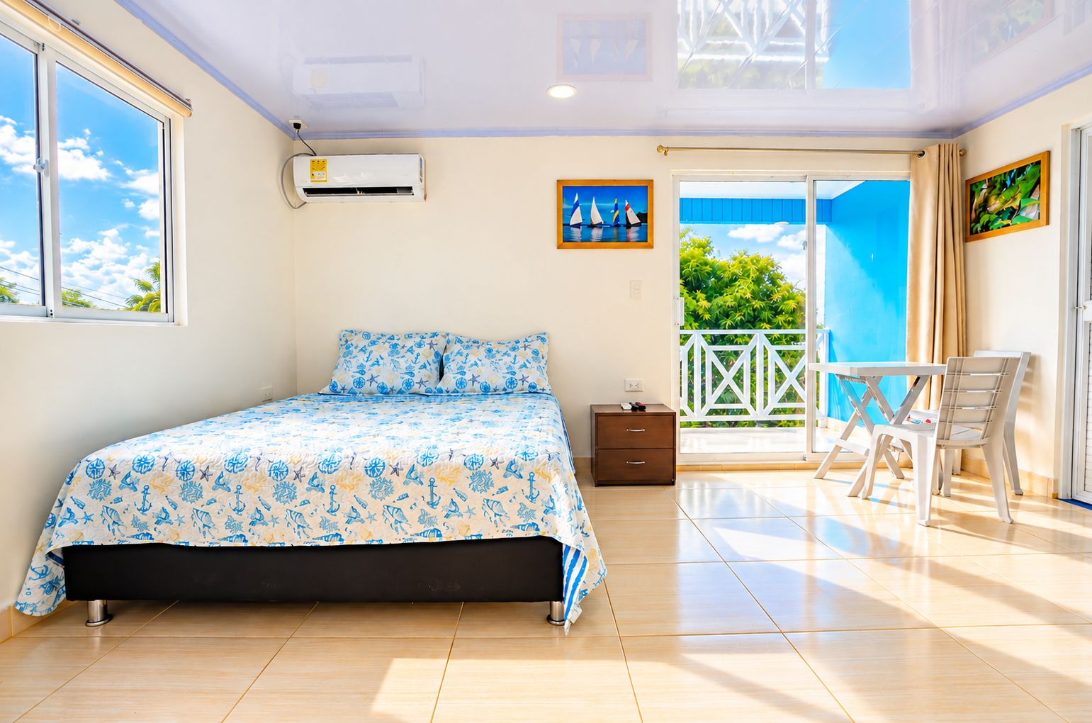 A bedroom with a bed, a nightstand, a window, and a balcony with a table and chairs.