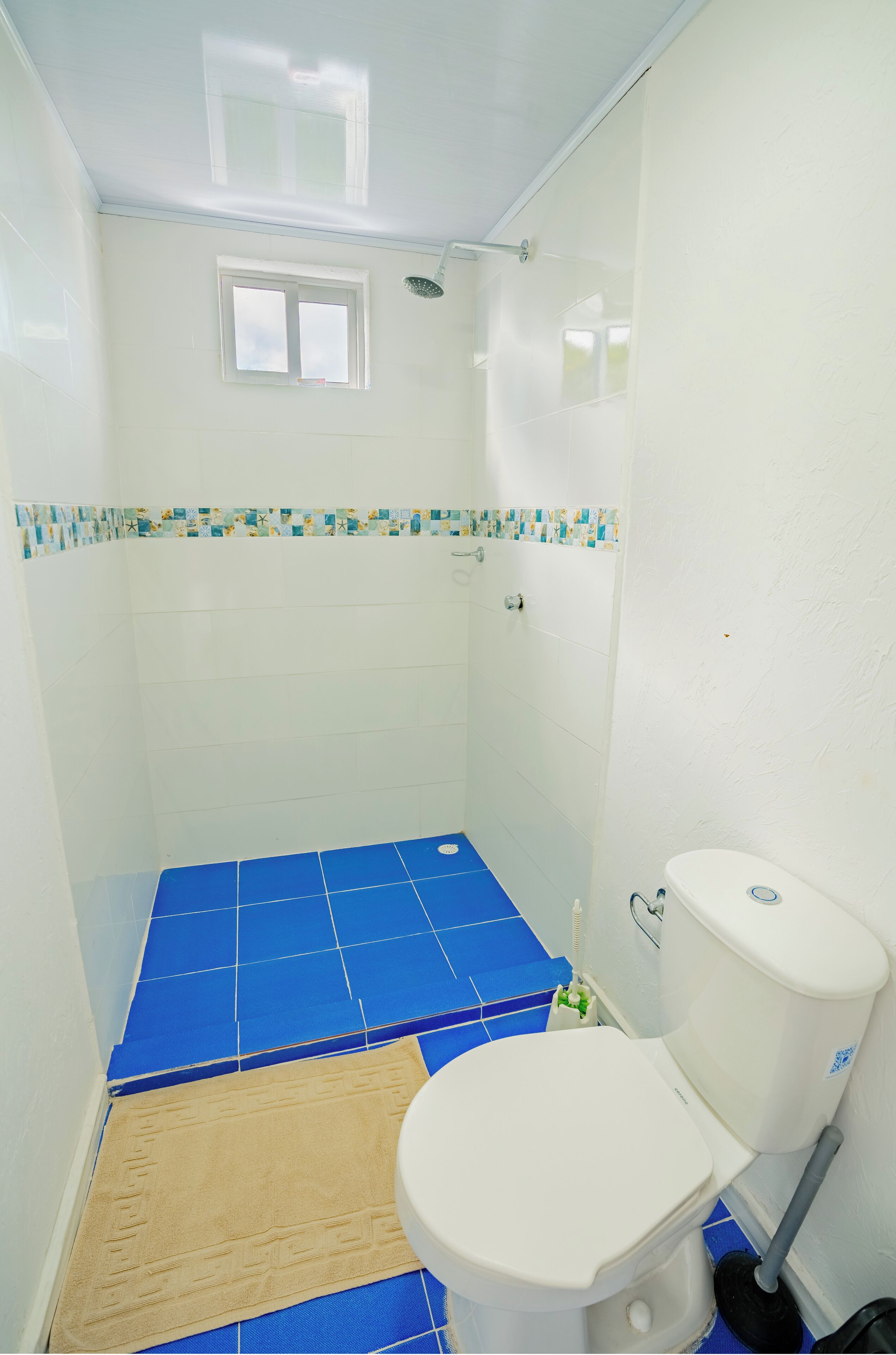 Ein Badezimmer mit Dusche, Toilette und blauen Fliesen.