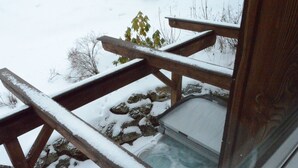 A wooden deck with a stone ledge and a glass enclosure. - Dreamy Chalet on the Slopes (Sankt Georgen am Kreischberg)