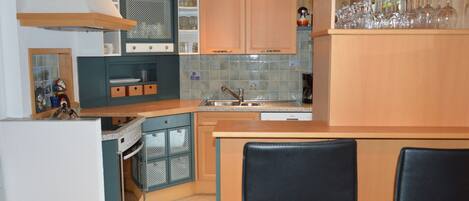 Una cocina compacta con armarios de madera, un lavamanos y un pequeño comedor con dos sillas.