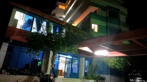 A multi-story building with a modern design, featuring a prominent entrance with glass doors and a staircase leading to the upper floors. - Nilanjana Kuakata (Kalapara)