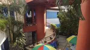 A courtyard with outdoor seating, a staircase, and a building with a balcony. - Nilanjana Kuakata (Kalapara)