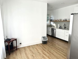 Kitchen features a stainless steel refrigerator, wooden table, and window with a view.