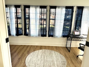 Relax in this serene space with a large window, wooden floor, and a comfortable chair.