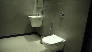 Egy modern fürőszoba fehér mosdókagylóval, WC-vel és zuhanyzóval.