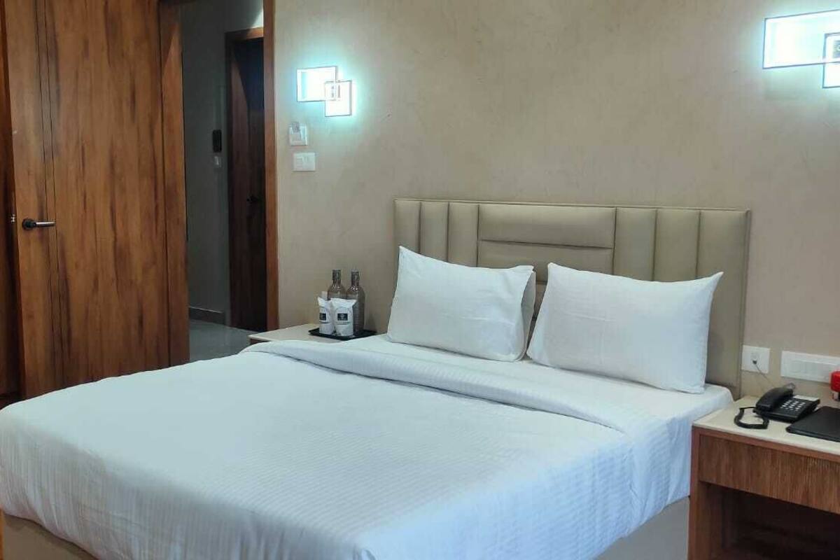Ein Hotelzimmer mit einem Bett, einem Holzschrank, einem Nachttisch mit Telefon und einem Beistelltisch.