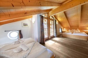 A bedroom with a sloped ceiling, a bed, a window, and a door. - Alpine Chalet in Wald im Pinzgau for 12 (Wald im Pinzgau)