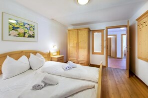 Une chambre d’hôtel avec un lit, une table de chevet, une lampe, une armoire en bois et un tableau représentant des fleurs.
