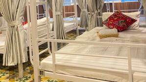 A hotel room with bunk beds, curtains, a patterned floor, and a colorful pillow. - Hanoi Vibes Hostel (Hanoi)