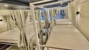A train carriage with multiple berths, each with a white metal frame and a mattress. - Hanoi Vibes Hostel (Hanoi)