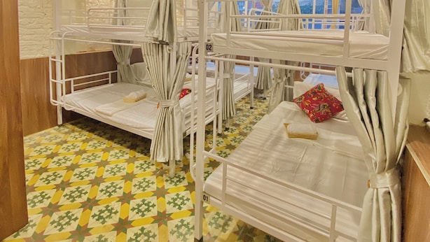 A dormitory room with bunk beds, curtains, and patterned flooring. - Hanoi Vibes Hostel (Hanoi)