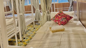 A bunk bed room with a window, curtains, and a colorful floor pattern. - Hanoi Vibes Hostel (Hanoi)