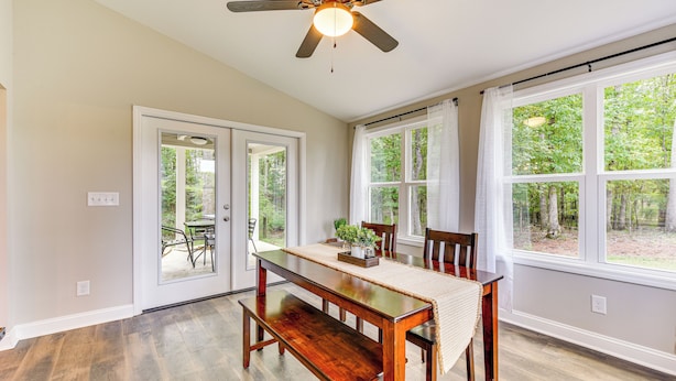 A dining area with a wooden table, chairs, and a ceiling fan.
