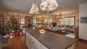 Un salón espacioso con una isla grande de madera, una cocina con detalles de piedra y una chimenea acogedora.