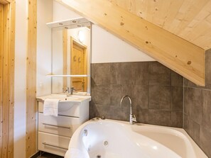 A modern bathroom with a freestanding bathtub, a vanity with a mirror, and wooden paneling on the walls. - Exclusive Chalet With Whirlpool (Sankt Georgen am Kreischberg)