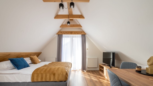 A bedroom with a bed, a desk, a chair, a television, and a window with curtains. - Ornak 7 (Zakopane)