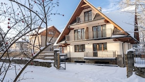 A two-story chalet with a balcony, stone foundation, and a sign indicating it is unit number 7. - Ornak 7 (Zakopane)