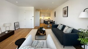 A modern living room with a sofa, coffee table, and a dining area in the background.