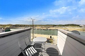 Enjoy breathtaking views of the marina from this balcony, featuring a table and chair.