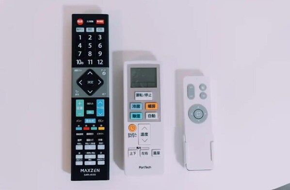 Three remote controls: a black MAXZEN MR-600, a white PortTech remote, and a white remote with a circular button layout. - Minimalist Loft 501 (Osaka)