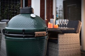 Un grand barbecue extérieur vert, doté d’un indicateur de température et d’une étiquette sur laquelle on peut lire « Big Green Egg ».