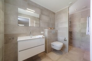 Une salle de bain moderne avec un meuble-lavabo blanc, des toilettes, un espace douche et un grand miroir.