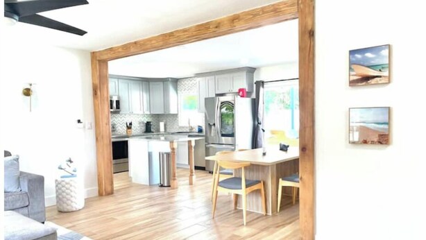 Une cuisine moderne dotée d’un îlot central, de planchers en bois et d’un coin repas avec des chaises.