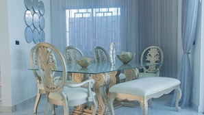 A dining area with a glass-top table, ornate chairs, and a white bench. - Charming 3-bedroom house with AC, WiFi in delightful Bocachica (Bocachica)