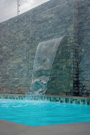Un muro in pietra con una cascata di fronte.