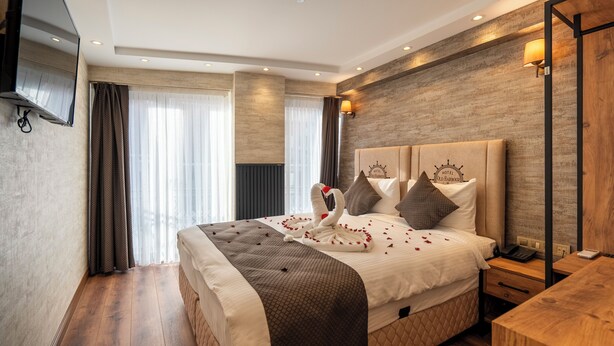 Une chambre d’hôtel avec un grand lit, un téléviseur à écran plat fixé au mur, une table de chevet en bois et un bureau en bois.