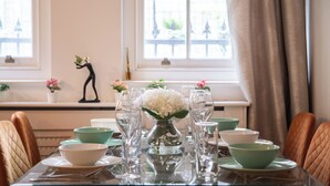 Una mesa de comedor dispuesta con cuencos, platos y vasos verdes y blancos, con un jarrón de flores blancas en el centro.