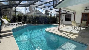 A clear blue pool with a glass ceiling, surrounded by lounge chairs and a covered patio area. - POOL House+Garage. Bring your Bikes! + 3Bed/2Bath
 (Port Orange)