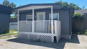 A small, single-story building with a white porch and a covered area. - Tiny home Rental (Houston)