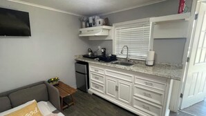 A compact kitchen with white cabinets, a built-in sink, and a countertop. - Tiny home Rental (Houston)