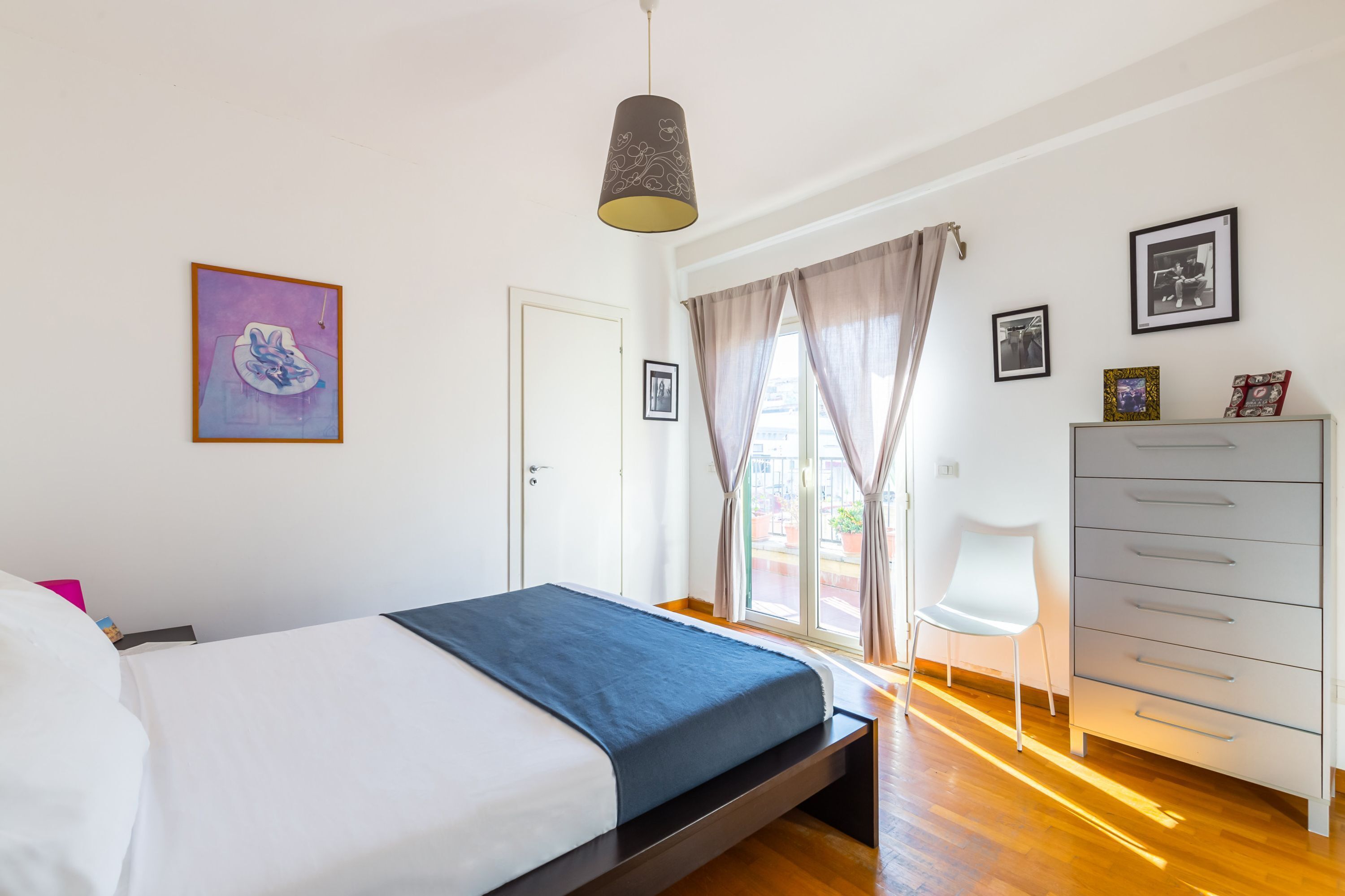 A bedroom with a bed, a dresser, a chair, and a window with curtains.