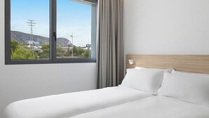 A hotel room with a large bed, a view of the outside, and a wooden headboard. - B&B Hotel MADRID Carabanchel (Madrid)
