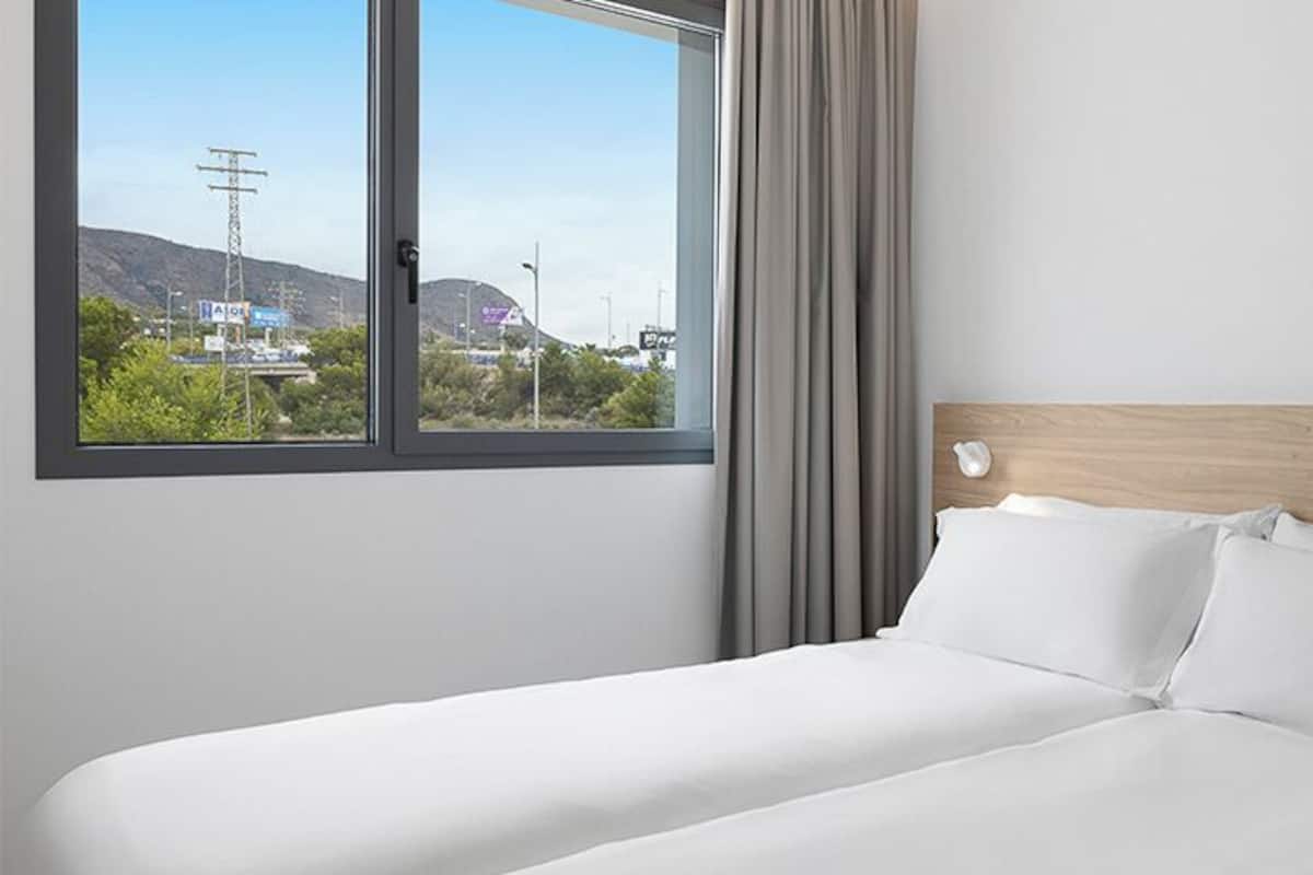 Une chambre d’hôtel avec un grand lit, une vue sur l’extérieur et une tête de lit en bois.