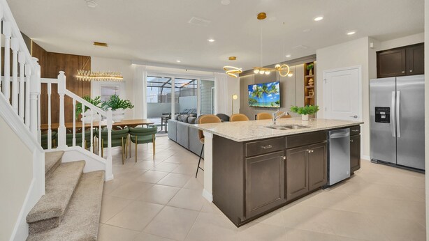 A modern kitchen with a central island, stainless steel appliances, and a dining area with a sofa and chairs.