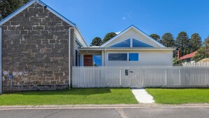 A two-story house with a stone facade and a white picket fence. - The Sunshine House - Nestled in the heart of the city. (Warrnambool)