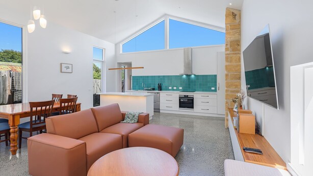 A modern kitchen with a large island, white cabinetry, and a teal backsplash. - The Sunshine House - Nestled in the heart of the city. (Warrnambool)