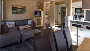 A modern living room with a sofa, a television, and a wooden wall. - Attractive Chalet With Whirlpool (Sankt Georgen am Kreischberg)