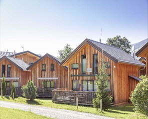 Een rij houten hutten met puntige daken, elk met een balkon en een klein terras.