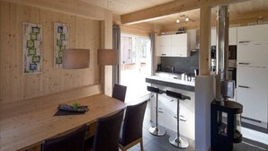 A modern kitchen with white cabinets, a black countertop, and stainless steel appliances. There is a wooden dining table with four chairs. - Attractive Chalet With Whirlpool (Sankt Georgen am Kreischberg)