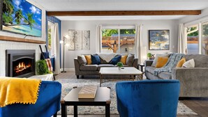A living room with a fireplace, two sofas, a coffee table, and a TV mounted on the wall. - Ultimate Group Getaway: Sleeps 16, Hot Tub, Arcade, & 5 Min from Mall of America (Minneapolis)