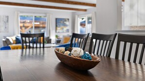 A dining area with a wooden table, a bowl of decorative items, and black and white striped chairs. - Ultimate Group Getaway: Sleeps 16, Hot Tub, Arcade, & 5 Min from Mall of America (Minneapolis)